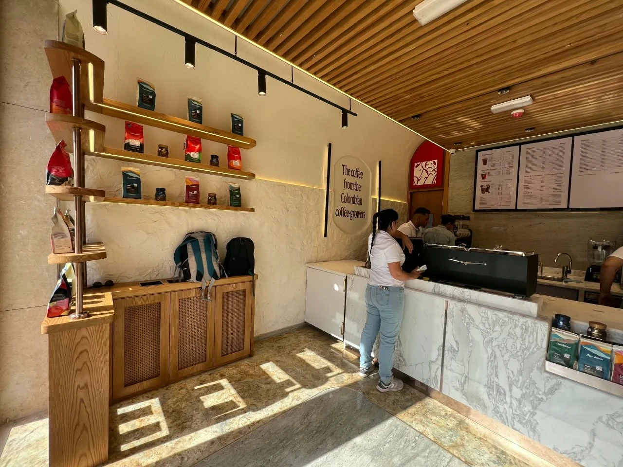 داخل كافيه بكونتر وكسوة حجرية ورفوف وسقف من شرائح خشبية